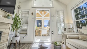 A modern interior with a wooden floor, a large TV, and a dining area visible through a door. - Biggie Smalls (Woodland Park)