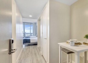 A hotel corridor with a bed, a bathroom with a sink, and a view of the outdoors. - Upper Studio with Stunning Views + Pool + Gym (Hallandale Beach)