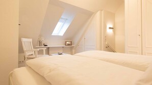 A bedroom with two beds, a chair, a desk, and a skylight. - 2-room apartment close to the beach, approx. 45 m² living space, for 2 people (Wenningstedt-Braderup (Sylt))