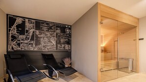 Ein moderner Wartebereich mit schwarzen Loungesesseln, einer großen Karte an der Wand und einer Holztür zu einem Raum.