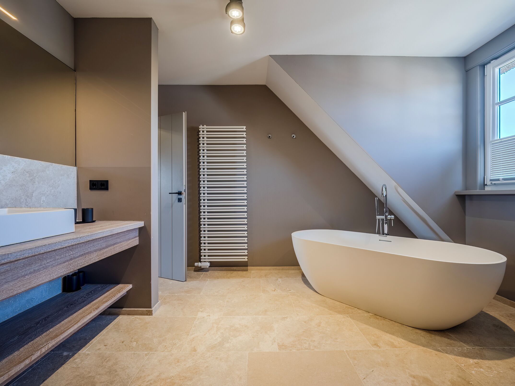A modern bathroom with a freestanding bathtub, a wooden vanity, and a towel rack.