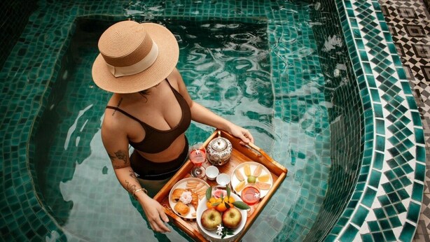 A person in a swimming pool holding a tray with food and drinks. - Studio apartment  Private bathtub, balcony, 45m2
 (Thành phố Hội An)