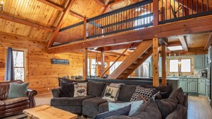 A wooden cabin interior with a living room, dining area, kitchen, and a staircase. - Stunning and Expansive 15 bedrooms Situated Close to Ski Slopes (McGaheysville)