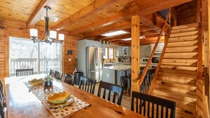 A wooden cabin interior with a dining area, kitchen, and staircase. - Stunning and Expansive 15 bedrooms Situated Close to Ski Slopes (McGaheysville)