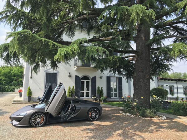 A modern building with a driveway and a parked sports car. - B&B VILLA PRESTIGIO (Novi Ligure)