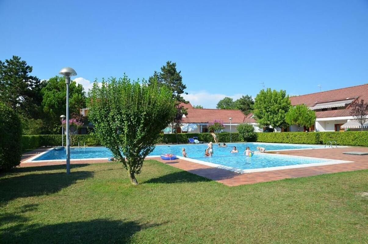 Ein Poolbereich mit zwei Pools, umgeben von gepflegtem Rasen und Bäumen.