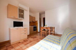 Una habitación funcional con cama, televisión, kitchenette y zona de comedor.
