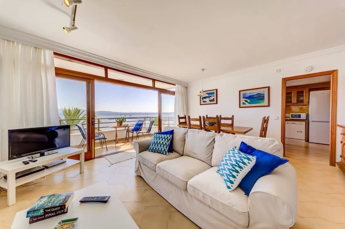 A modern living room with a sofa, TV, and a view of the sea.