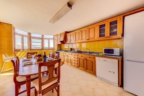 A kitchen with wooden cabinets, a dining table with chairs, a microwave, and a refrigerator.