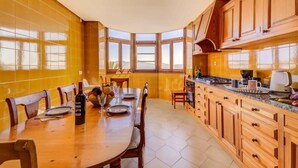 Una cocina con comedor, ventanas amplias y armarios de madera.