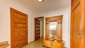 Un pasillo con puertas de madera, un mueble de espejo y una mesita.
