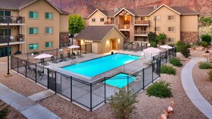 A hotel with a swimming pool, outdoor seating, and a view of red rock formations. - 6A Family Friendly RedCliff Condo POOL & HOT TUB (Moab)