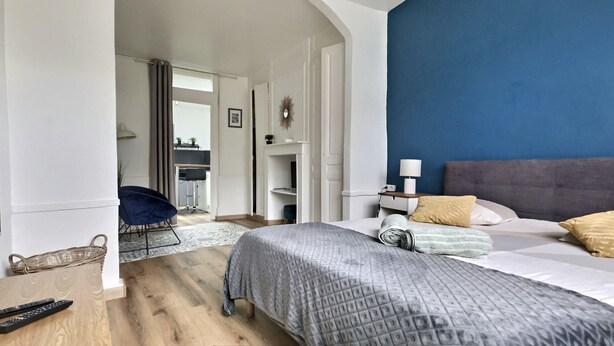 Een moderne slaapkamer met een groot bed, een nachtkastje en een blauwe accentmuur.