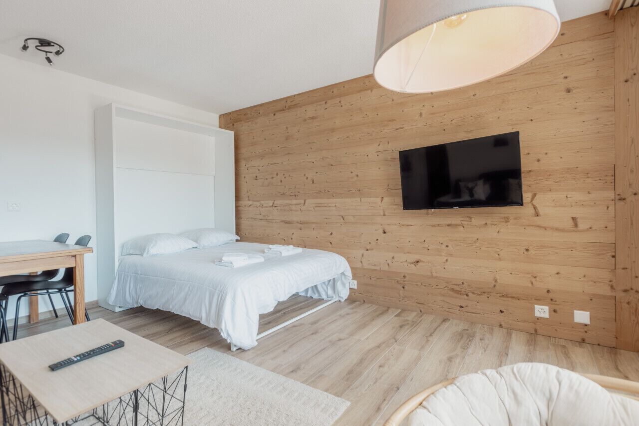 Une chambre moderne avec un mur en bois, un lit, un bureau et un téléviseur.