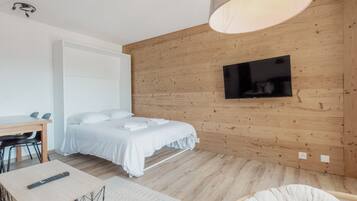 Une chambre moderne avec un mur en bois, un lit, un bureau et un téléviseur.