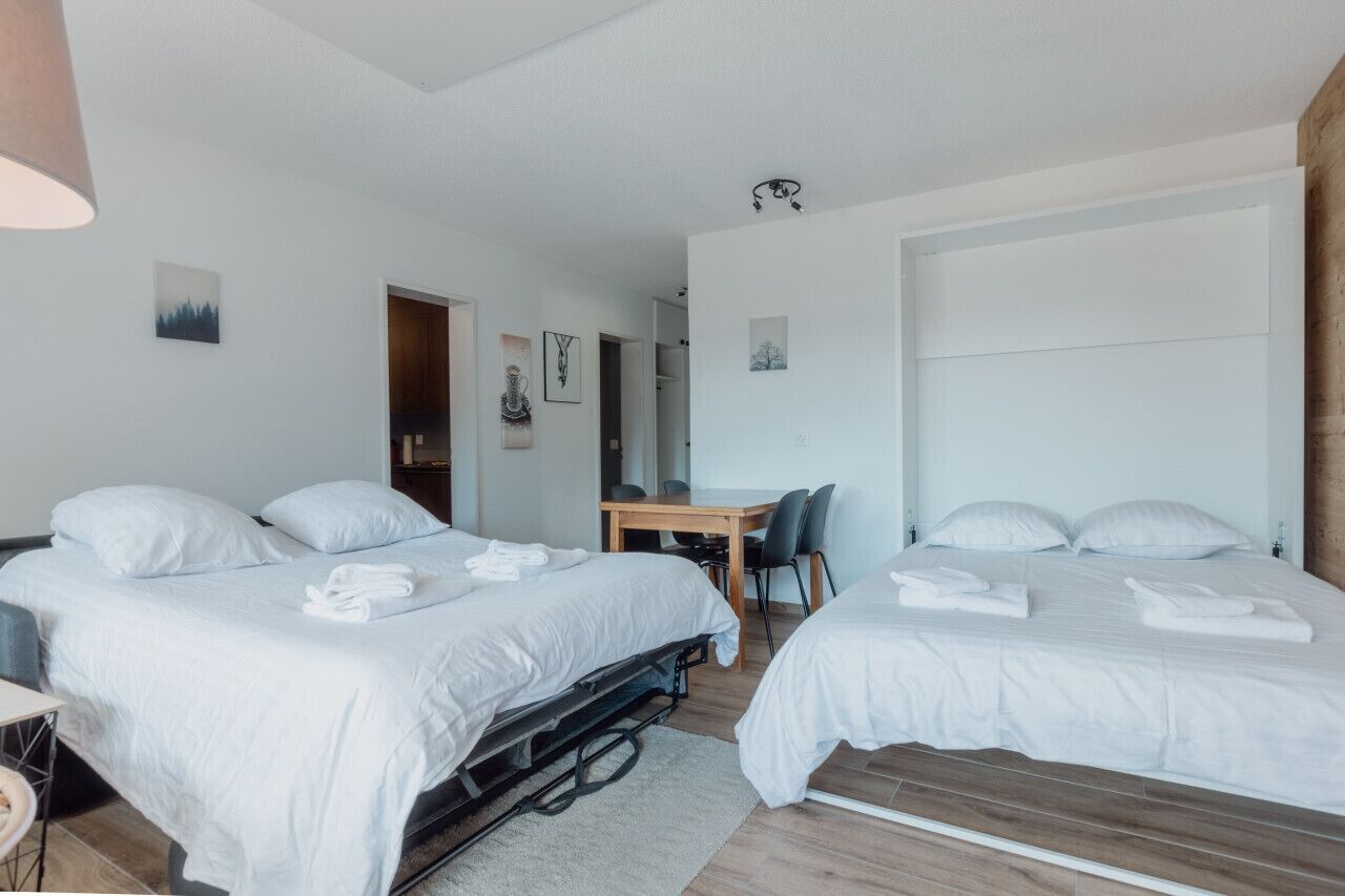 Een hotelkamer met twee bedden, een bureau en een stoel.