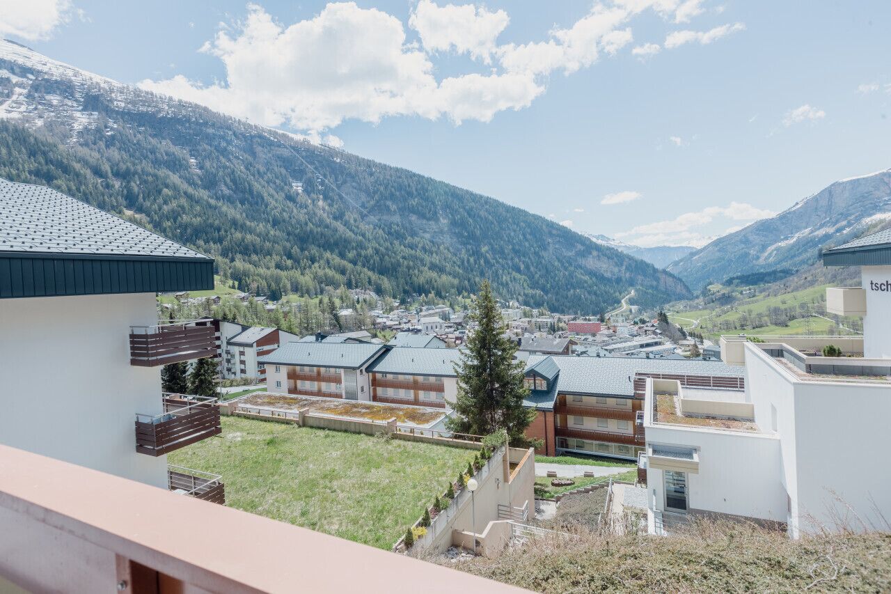 A modern building complex with multiple residential units, surrounded by a mountainous landscape.
