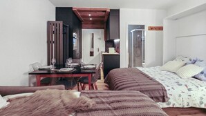 Ein Schlafzimmer mit zwei Betten, einem Esstisch und einem Duschbereich.