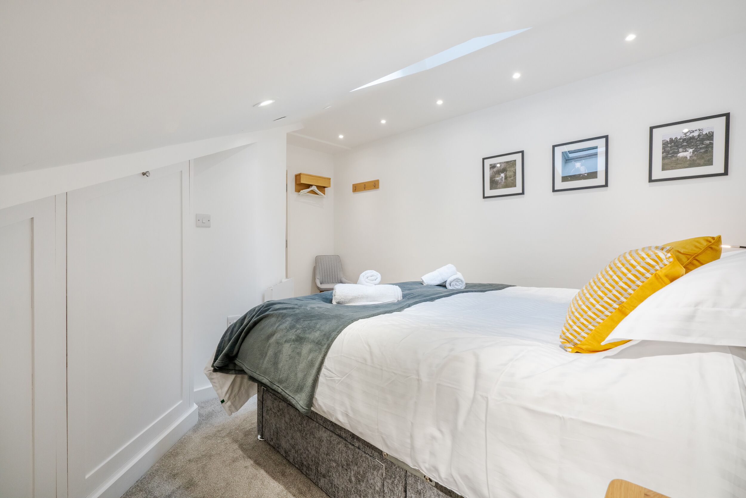 A bedroom with a bed, a wardrobe, a hanging rack, and a wall-mounted shelf.