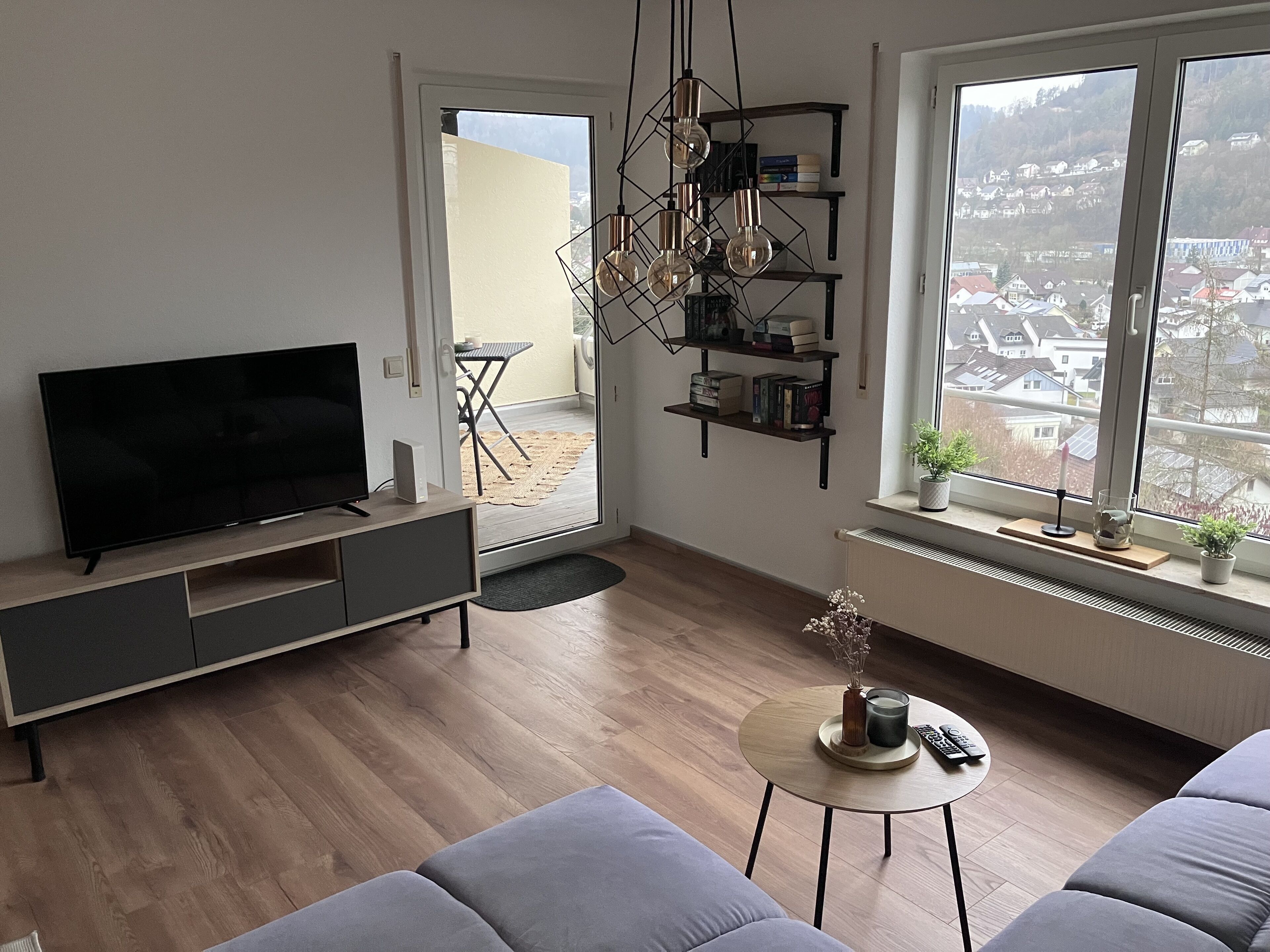 Una sala moderna con una televisión de pantalla plana, un sofá, una mesa de centro y una estantería.