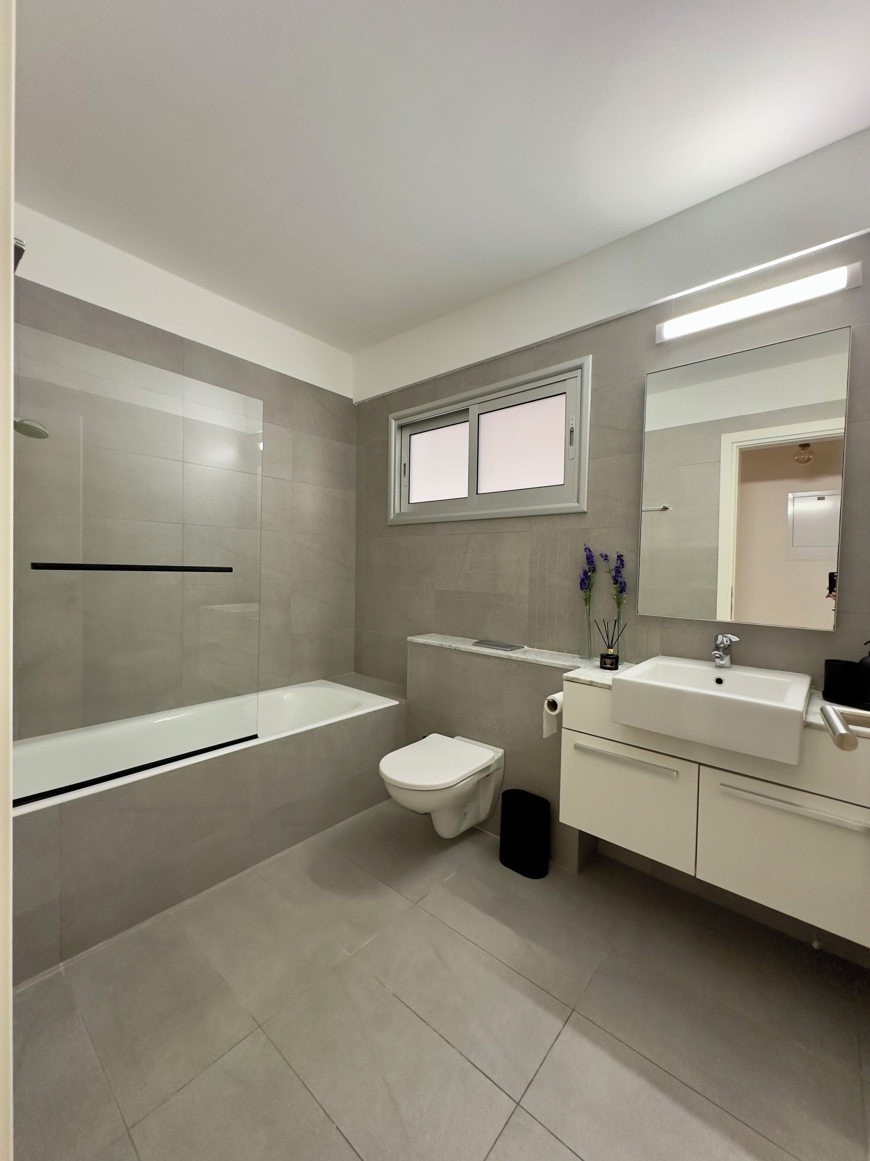 A modern bathroom with a bathtub, toilet, and vanity with a mirror.