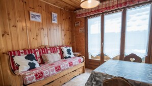 A wooden cabin interior with a sofa, table, and chairs. - Charming 1BR Apt, Balcony, Wi-Fi, Near Ski Lifts - Pets Welcome! (Les Gets)