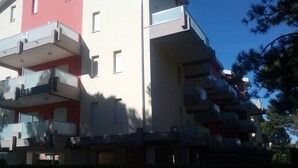 A multi-story residential building with balconies and a red facade. - Lovely Flat 100m From the Beach (San Michele al Tagliamento)