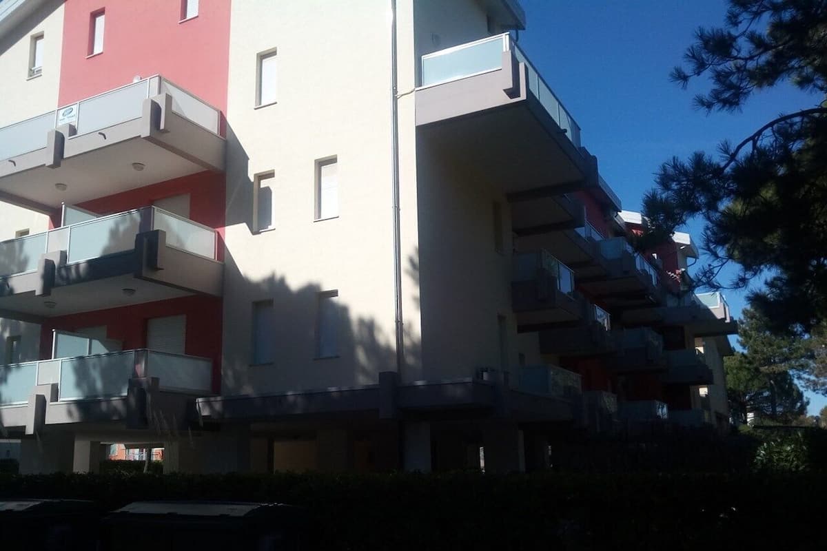 Ein mehrgeschossiges Wohngebäude mit Balkonen und einer roten Fassade.