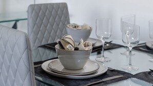 A dining area with a glass table set for four, including plates, bowls, and wine glasses. - Immaculate 2-bed Apartment in Hove (Hove)