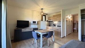 Un espace de vie compact comprenant une kitchenette, un coin repas et un téléviseur.