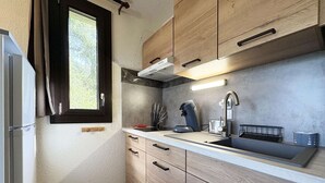 Une cuisine compacte avec des meubles en bois, un évier en acier inoxydable et une hotte intégrée.