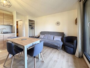 A compact living space with a kitchenette, a dining area, and a sofa.