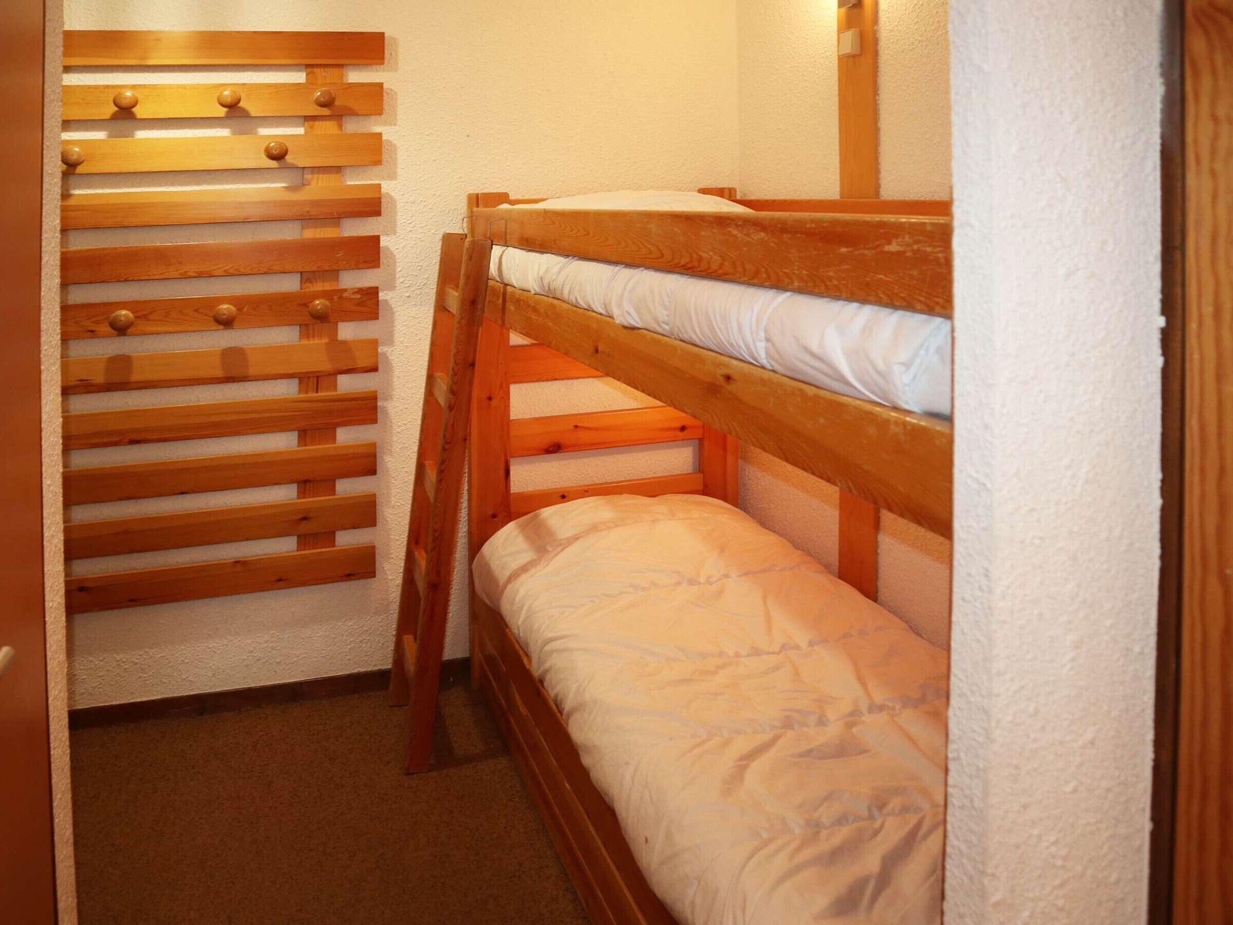 Ein Stockbett mit einem Holz-Kopfteil und einer unteren Liege.