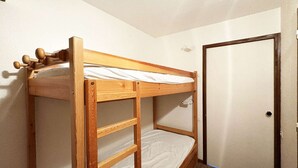 A bunk bed with a wooden frame and a ladder, a white door, and a carpeted floor.