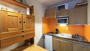 A compact kitchen with wooden cabinets, a microwave, a coffee maker, and a sink.