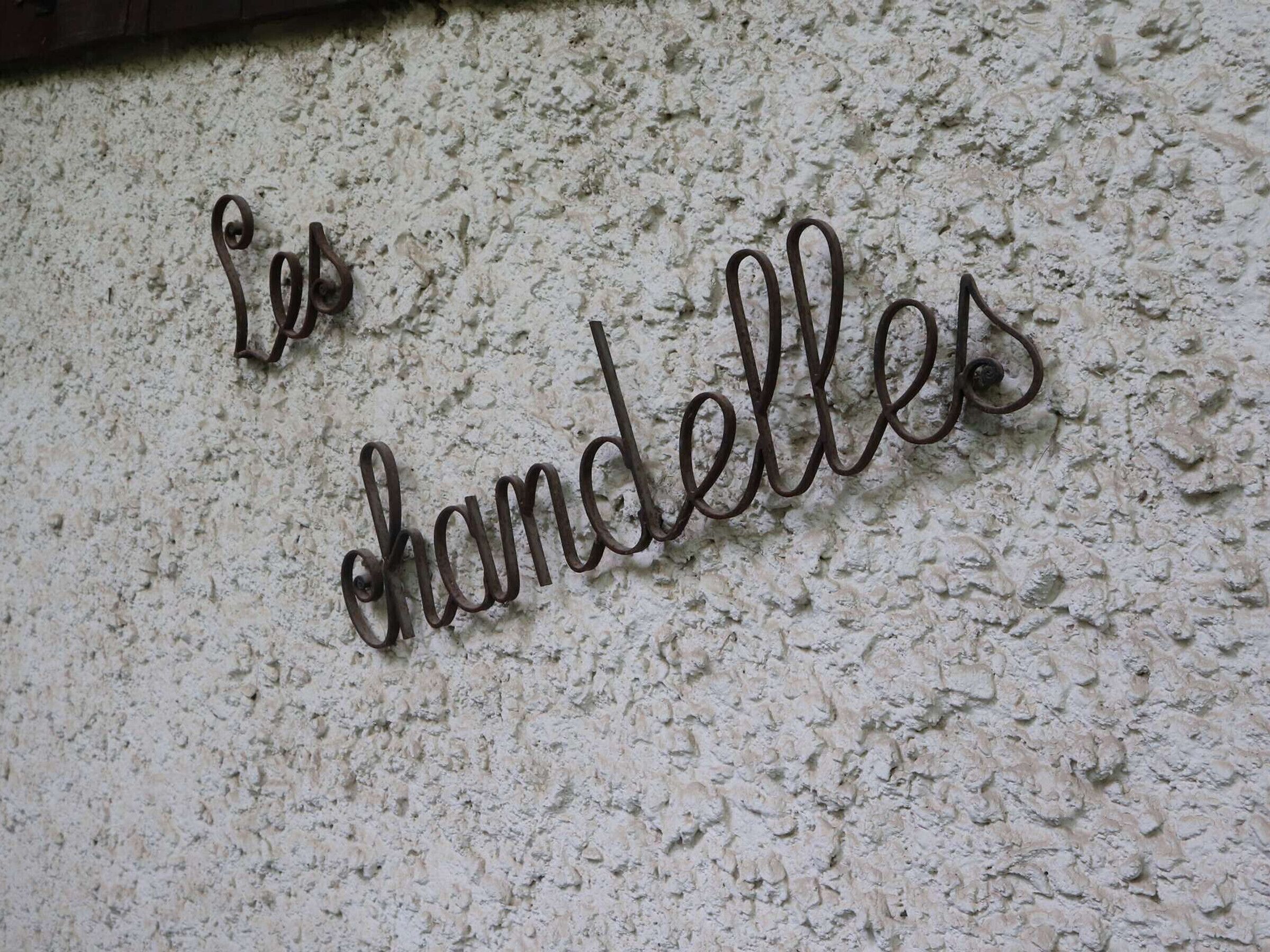 A textured wall with a metal sign spelling "les chandelles".