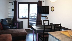 A compact living space with a sofa, a dining table with chairs, a TV, and a clock on the wall. - Bright studio for 4 in the heart of the resort with balcony (Les Orres)