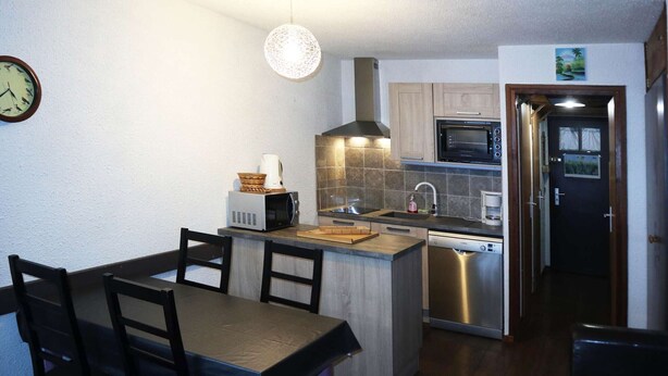 A compact kitchen with a dining area, featuring a microwave, stove, sink, and a clock on the wall. - Bright studio for 4 in the heart of the resort with balcony (Les Orres)
