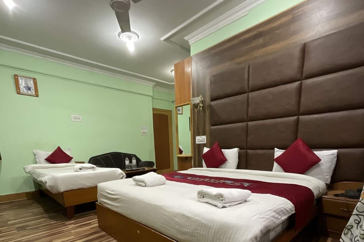 Quarto de hotel com duas camas, um ventilador de teto e piso de madeira.