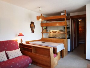 A cozy room with a wooden bunk bed, a small kitchenette, and a red sofa. - Apartment for 6 in Les Orres 1650 center with direct access to slopes (Les Orres)