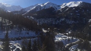 A mountainous landscape with snow-covered peaks and a valley with a winding road.