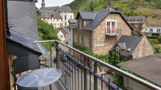 A balcony with a table and chairs, overlooking a town with stone buildings and a hill in the background. - The Studio Apartment Dornfelder Beilsteiner - Apartments MOSEL (Beilstein)