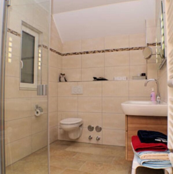 A bathroom with a toilet, sink, and glass shower enclosure.
