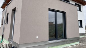 Ein modernes Gebäude mit flacher Fassade, großen Schiebeglastüren und einem geneigten Dach.