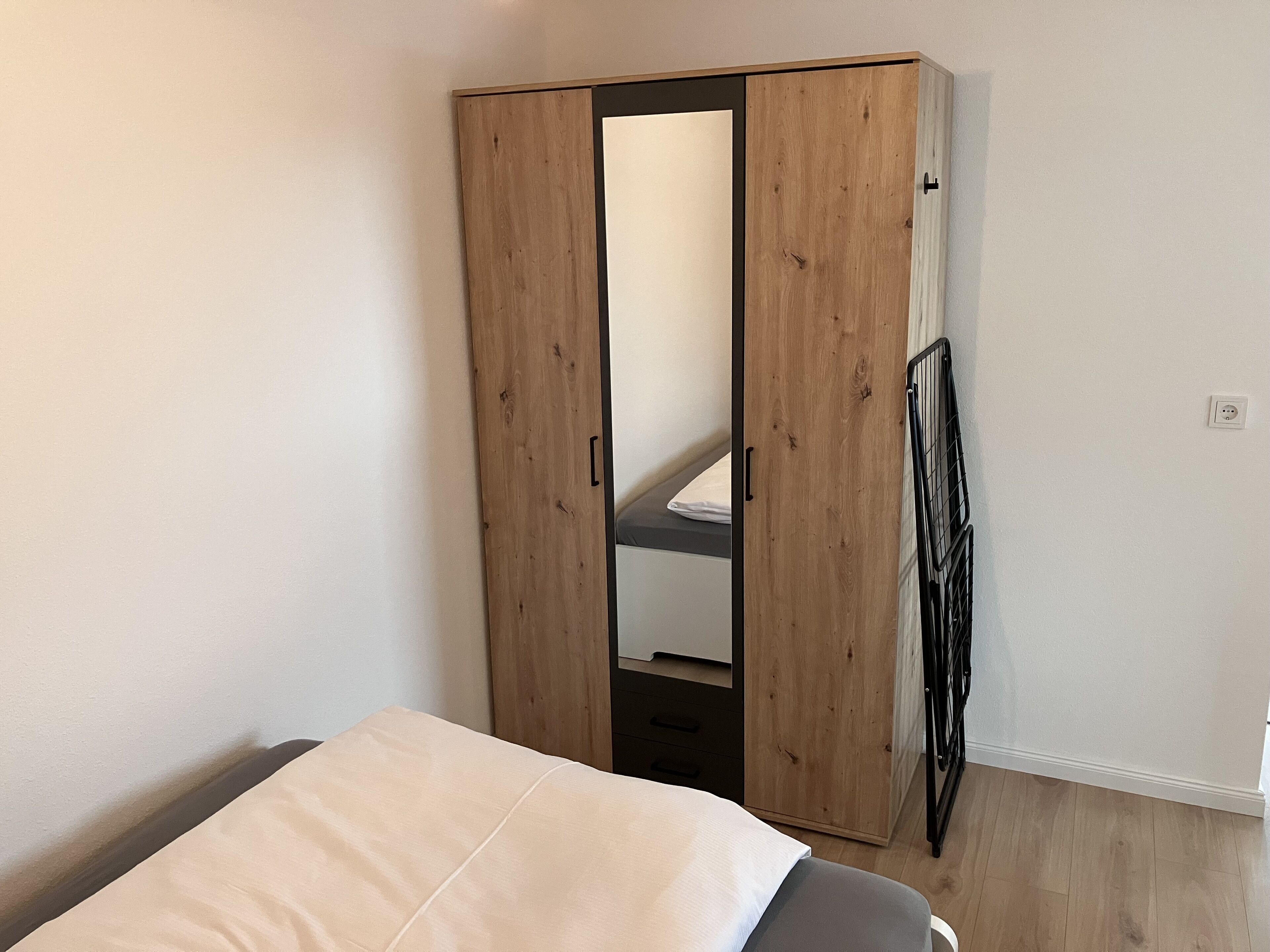 A bedroom with a bed, a wardrobe, and a radiator.
