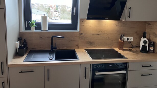 Eine moderne Küche mit Fenster, Backofen und Flachbildfernseher.