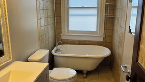 Un baño con bañera, inodoro y ventana.