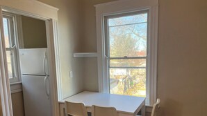 Una cocina pequeña con un refrigerador blanco, una mesa blanca y dos sillas blancas.