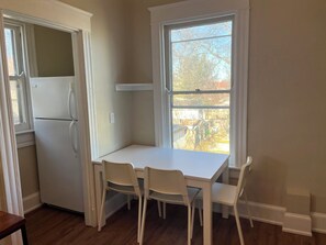 A small kitchen with a white refrigerator, a white table, and two white chairs.