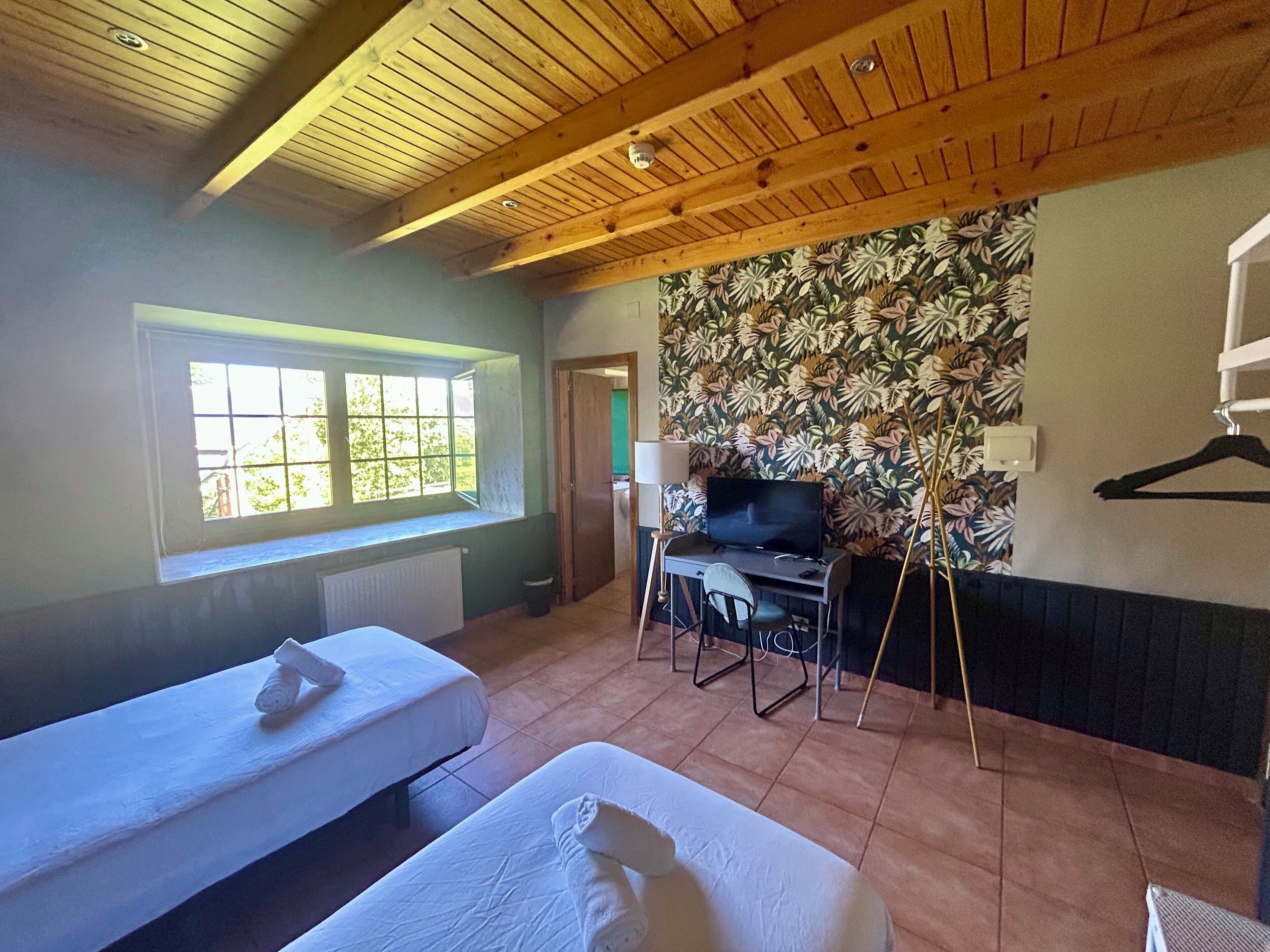 A room with two beds, a TV, and a desk.